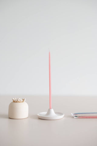 Giving set that includes a pack of pastel beeswax candles, a handmade ceramic candle holder and match striker. Pink candle in candle holder.