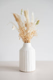 Ceramic peel-carved vase handmade in Canada and finished in a satin white glaze with a dried neutral floral arrangement.