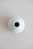Ceramic round bud vase in white with natural specs from the over view.