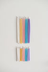 Rainbow of pastel gala candles above birthday candles.