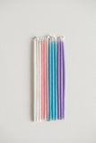 Rainbow of pastel gala beeswax candles in pearl, pink, teal and purple.