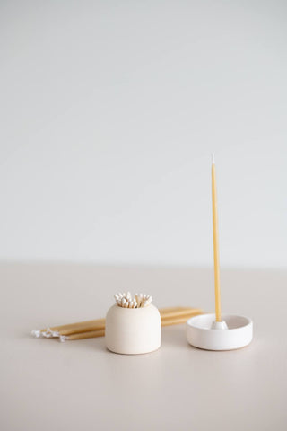 Giving set that includes a pack of natural beeswax candles, a handmade ceramic candle holder and match striker.