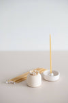 Giving set that includes a pack of natural beeswax candles, a handmade ceramic candle holder and match striker.