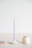 Giving set that includes a pack of pastel beeswax candles, a handmade ceramic candle holder and match striker. Purple candle in candle holder.
