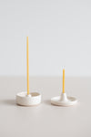 Natural beeswax gala candle in a handmade ceramic candle holder beside a natural beeswax birthday candle in a ceramic candle holder.